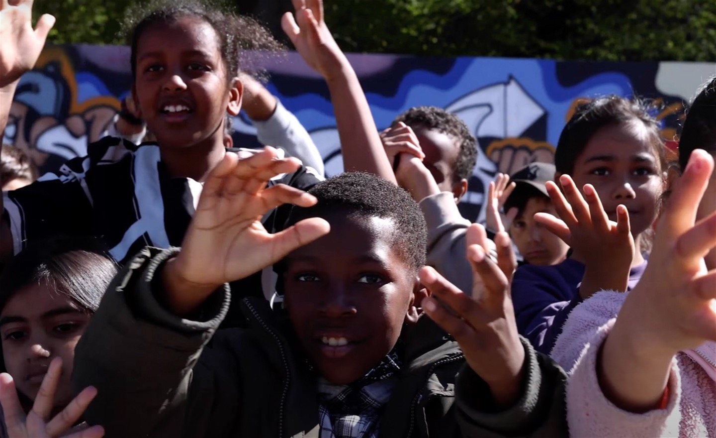 Glada barnansikten och viftande händer. Bild tagen ovanifrån.