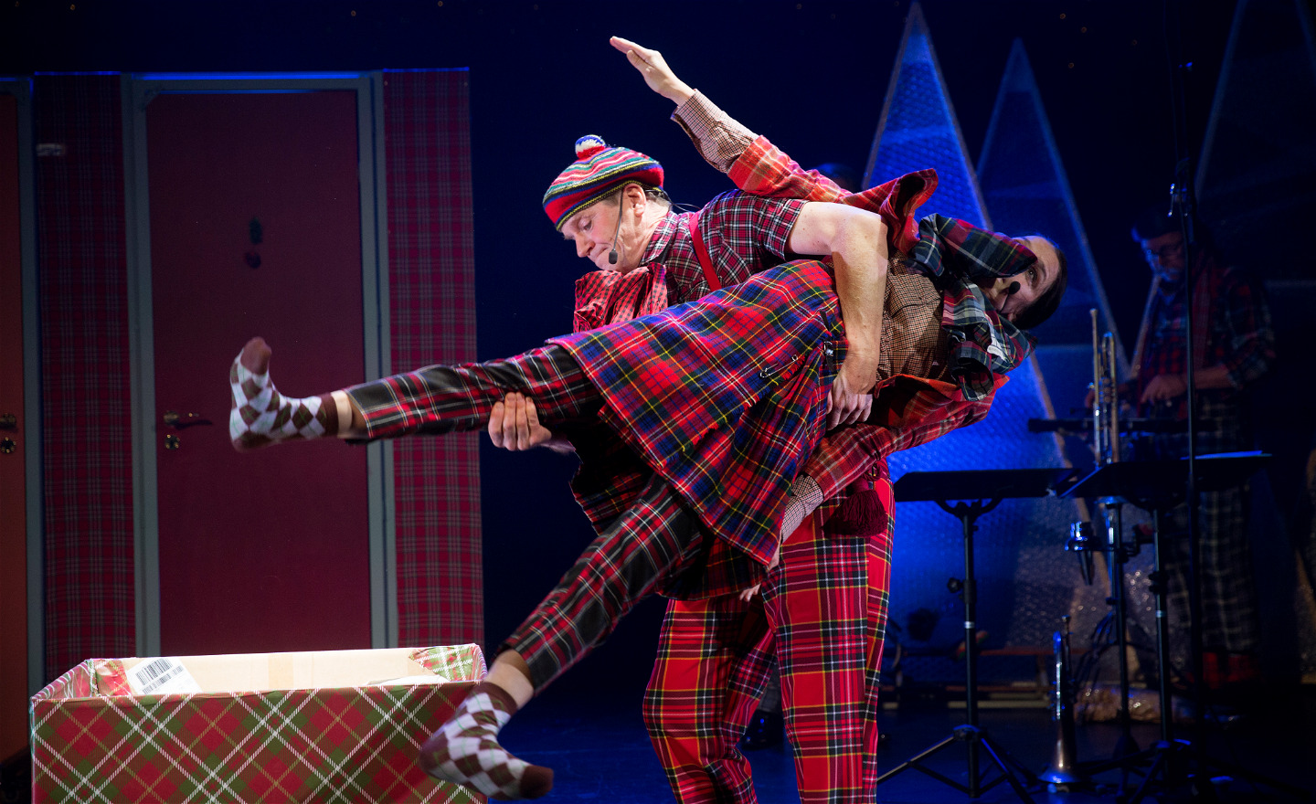 En skådespelare stel som en docka bärs av en annan skådespelare.