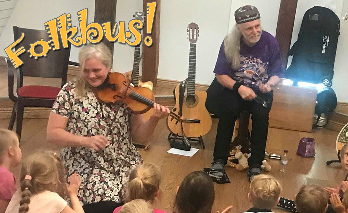 Folkbus: Två musiker med instrument och barnpublik