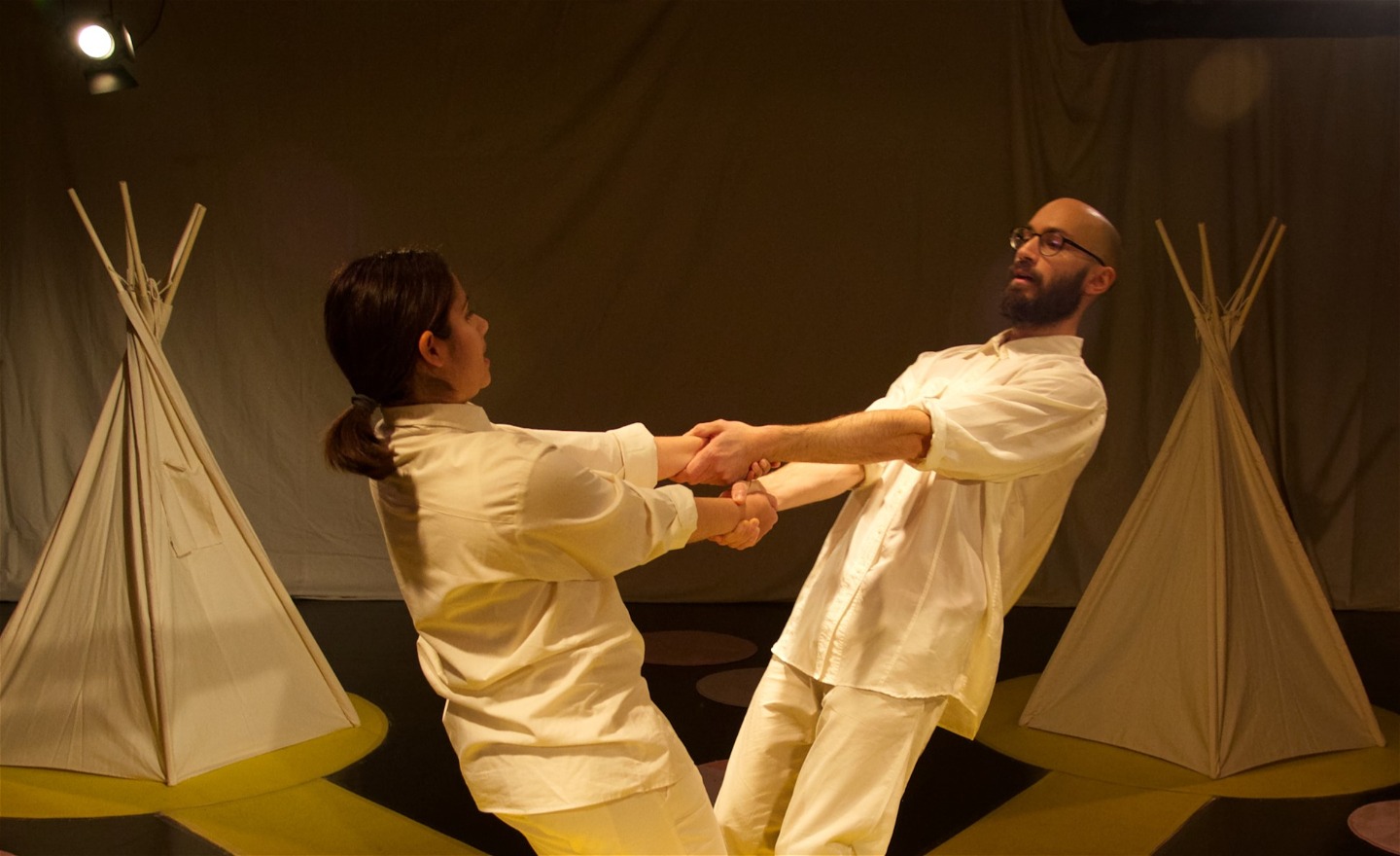 Två dansare i vita kläder håller tag i varandras händer