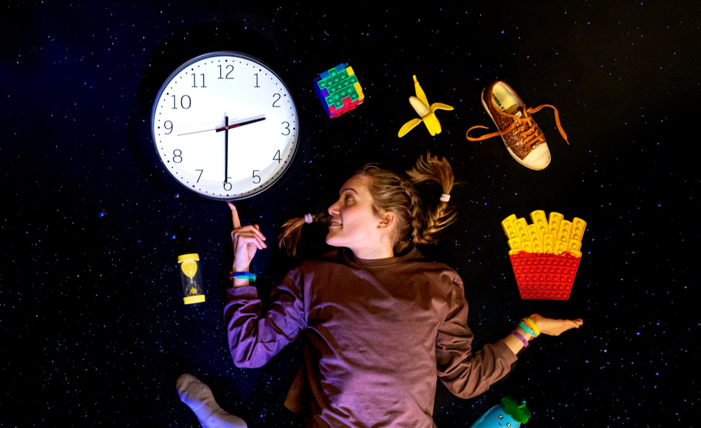 Flicka som bollar med olika figurer och pekar på klocka.