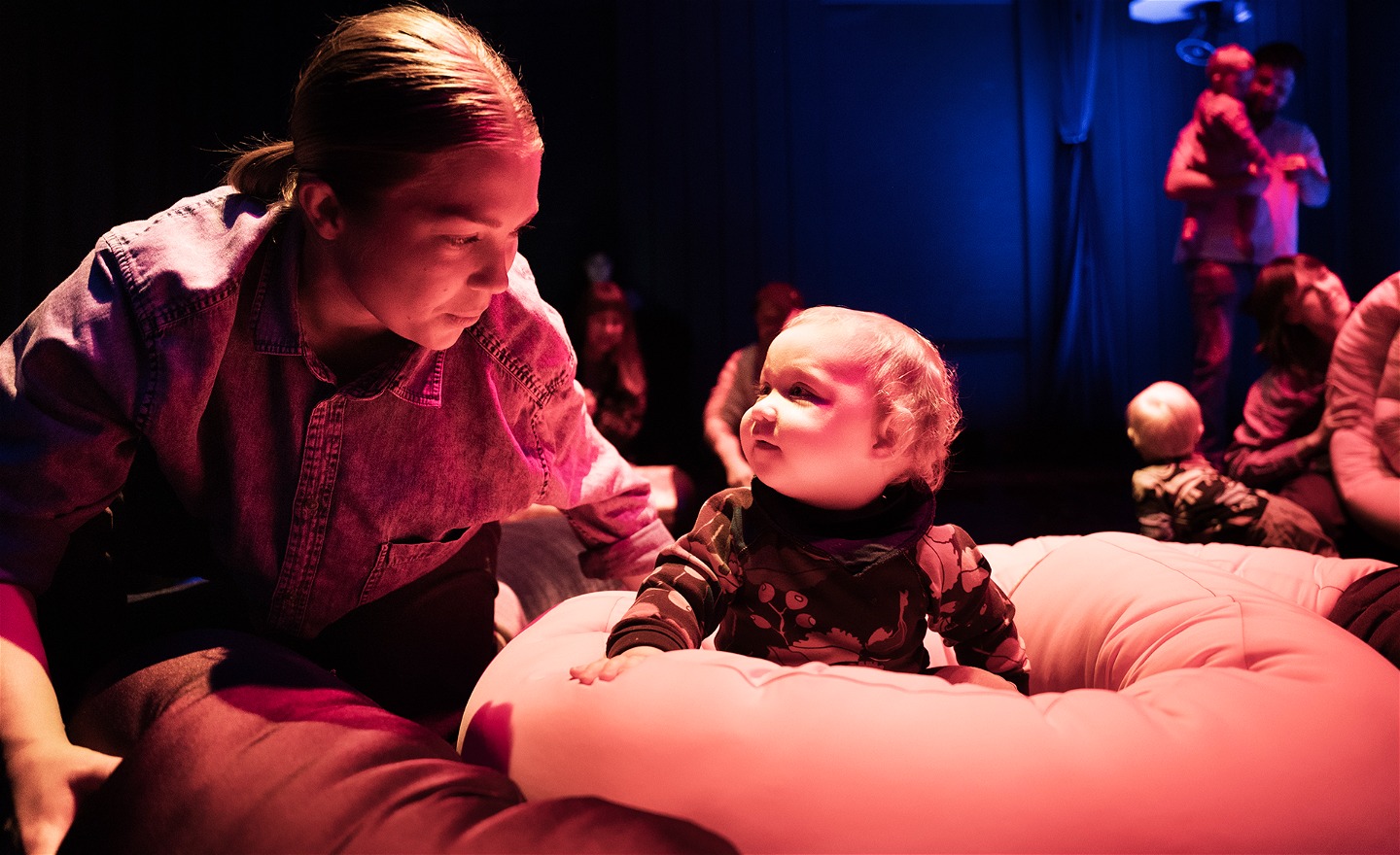 En dansare och ett litet barn tittar på varandra