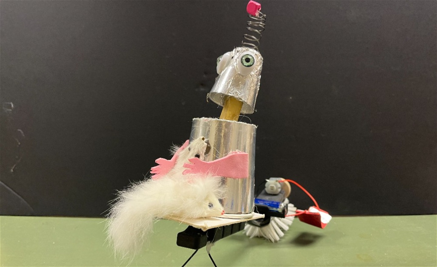 En robot med rosa händer och en fjäderkompis i famnen