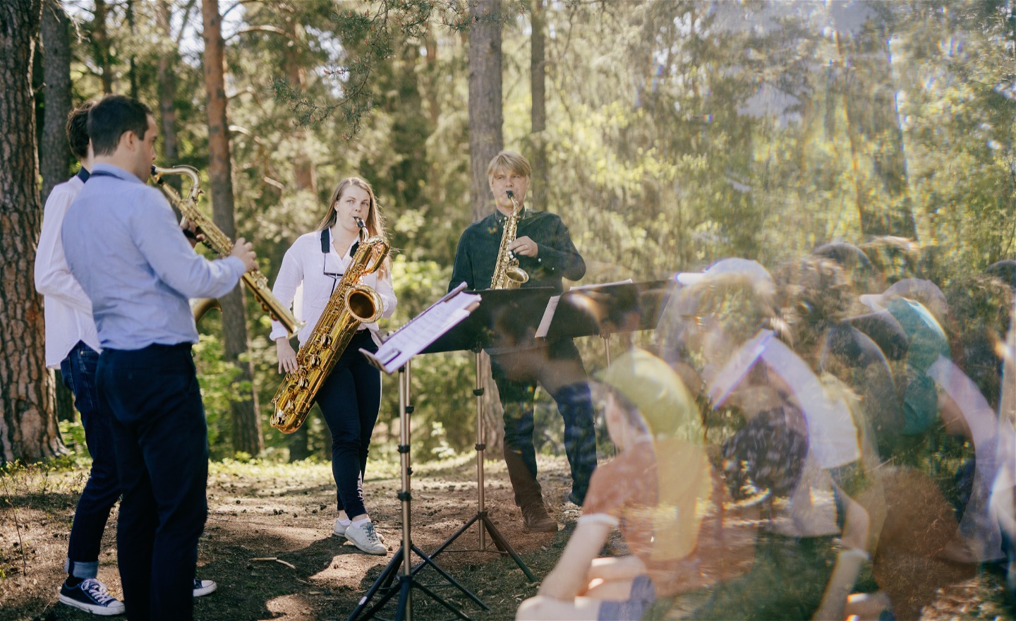 Stockholms Saxofonkvartet spelar i solig skog.