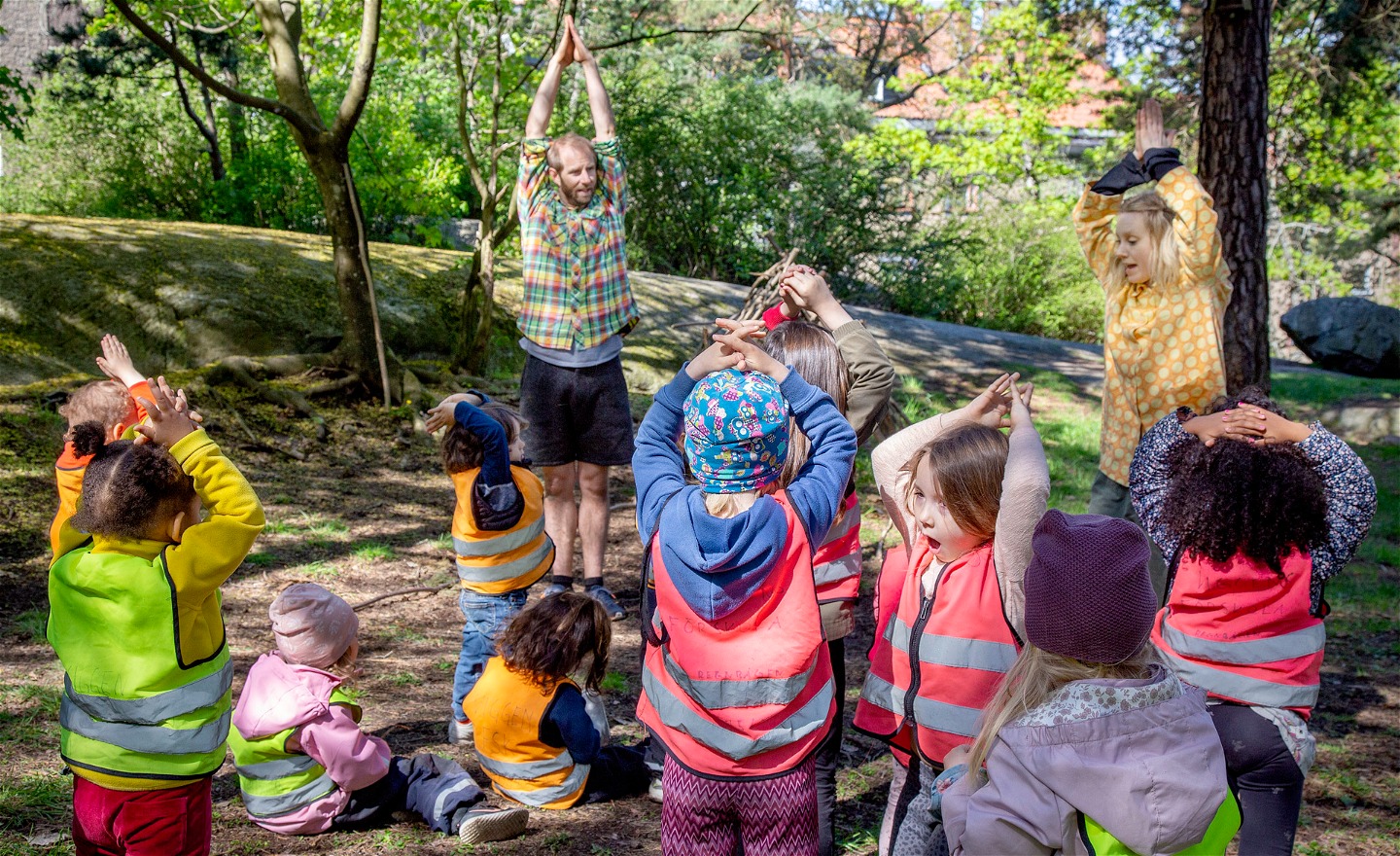 Barn som dansar utomhus i en skogsdunge bland träd och buskar med dansarna Anna och Oskar.