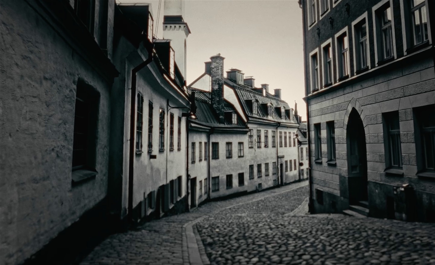 En svartvit bild som visar en gata i Stockholm med kullersten. 