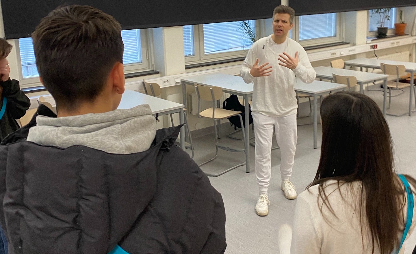 En skådespelare som pratar och instruerar några elever som viser ryggarna på.