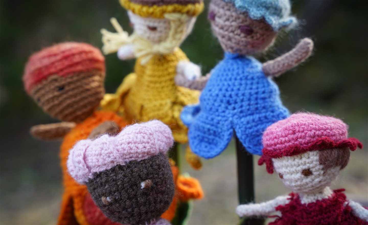 Fem st färgglada virkade dockor/blommor med ansikten