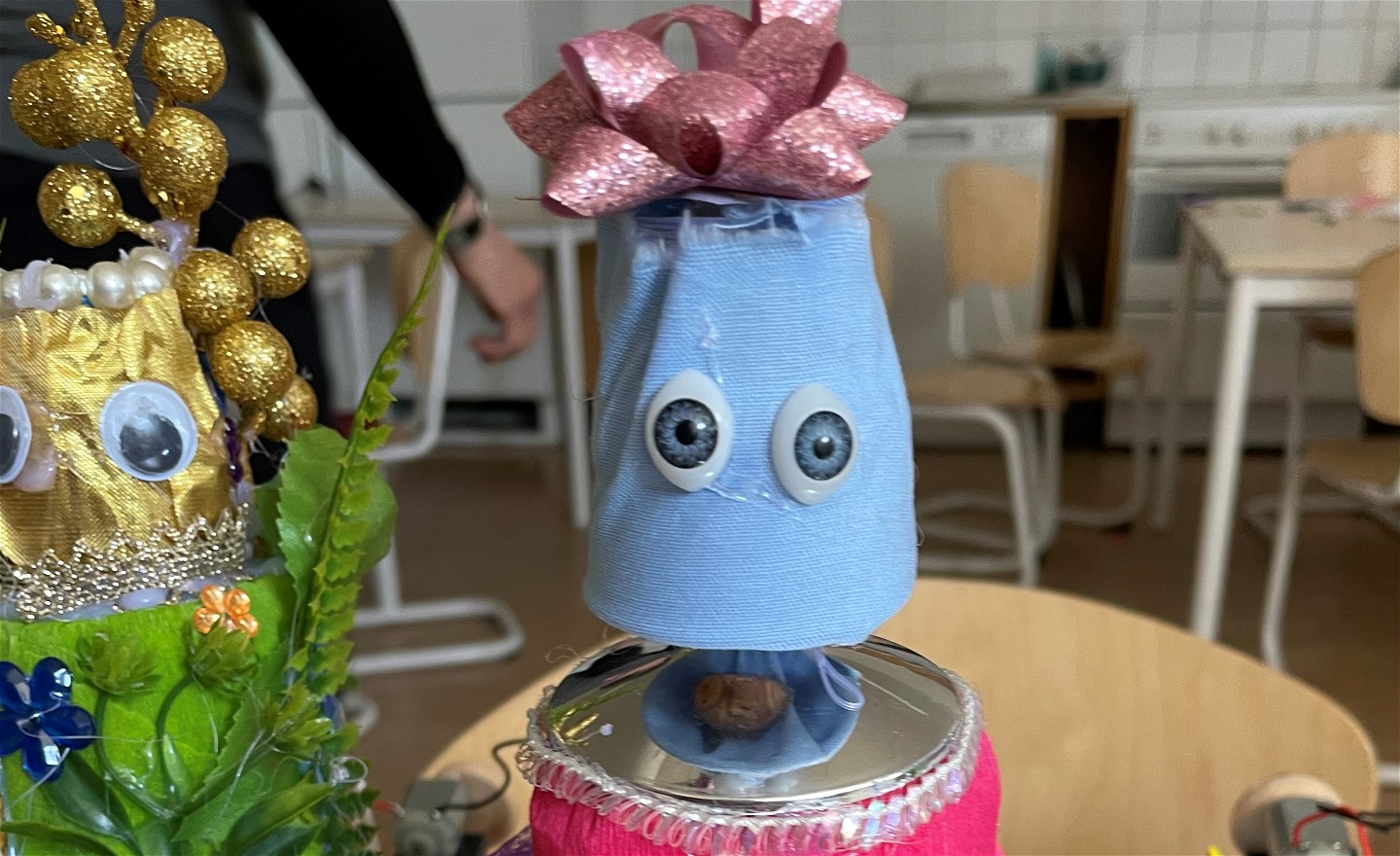 Två gulliga robotansikten. En med guldkulor ovanpå och en med rosett på huvudet