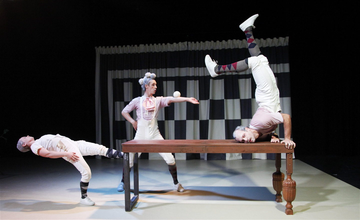 Tre akrobater runt ett matbord