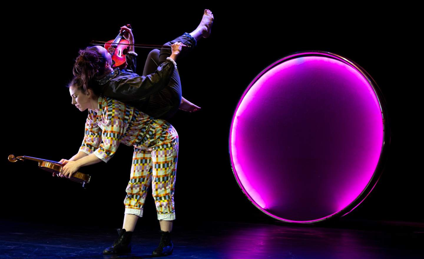 En violinist spelar liggande på ryggen av en akrobat.