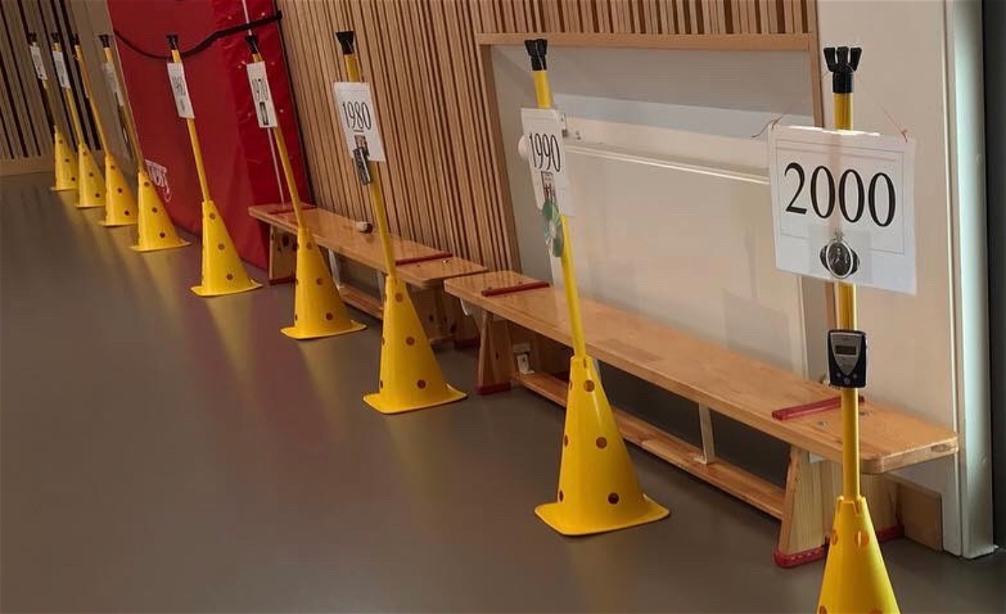 Gula koner med skyltar där det står olika årtal och det hänger olika tekniska uppfinningar under skyltarna.