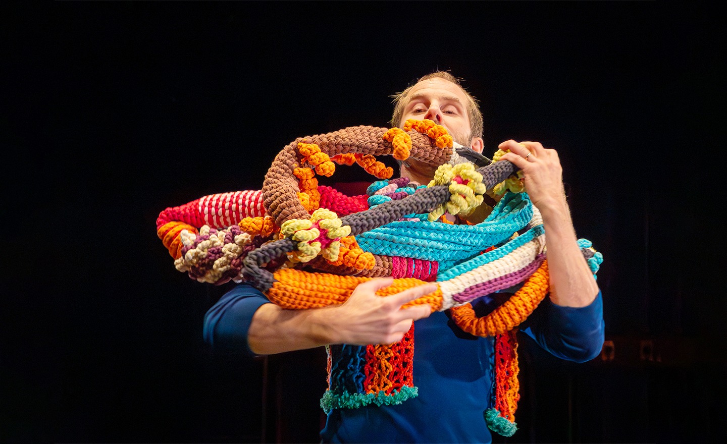 Oskar, som är dansare, håller långa virkade ormar i famnen