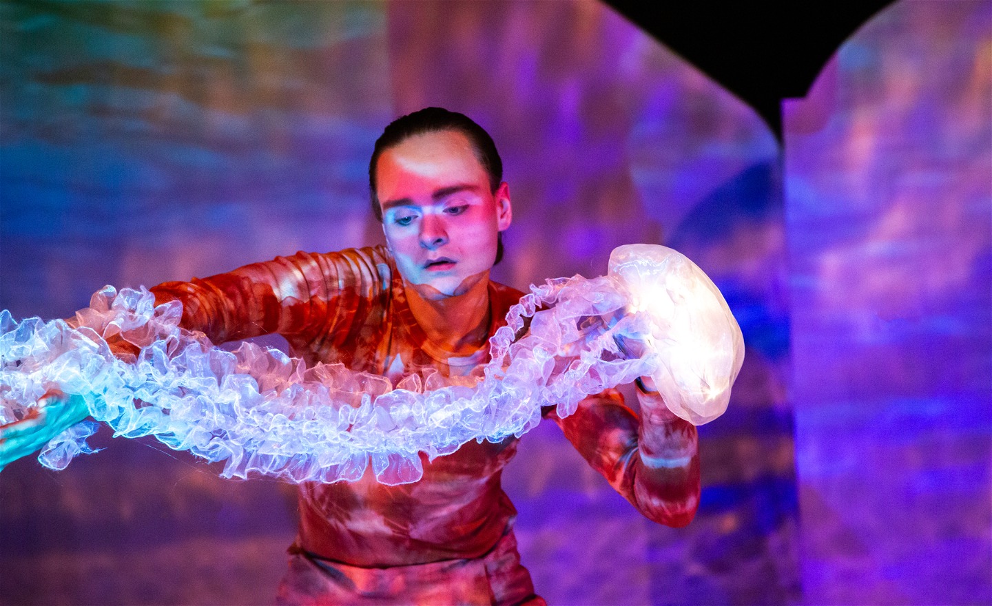 En person håller i en svävande lysande manetdocka