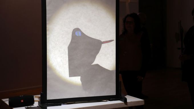 En skuggspelsteater på en vit skärm med svart ram.
