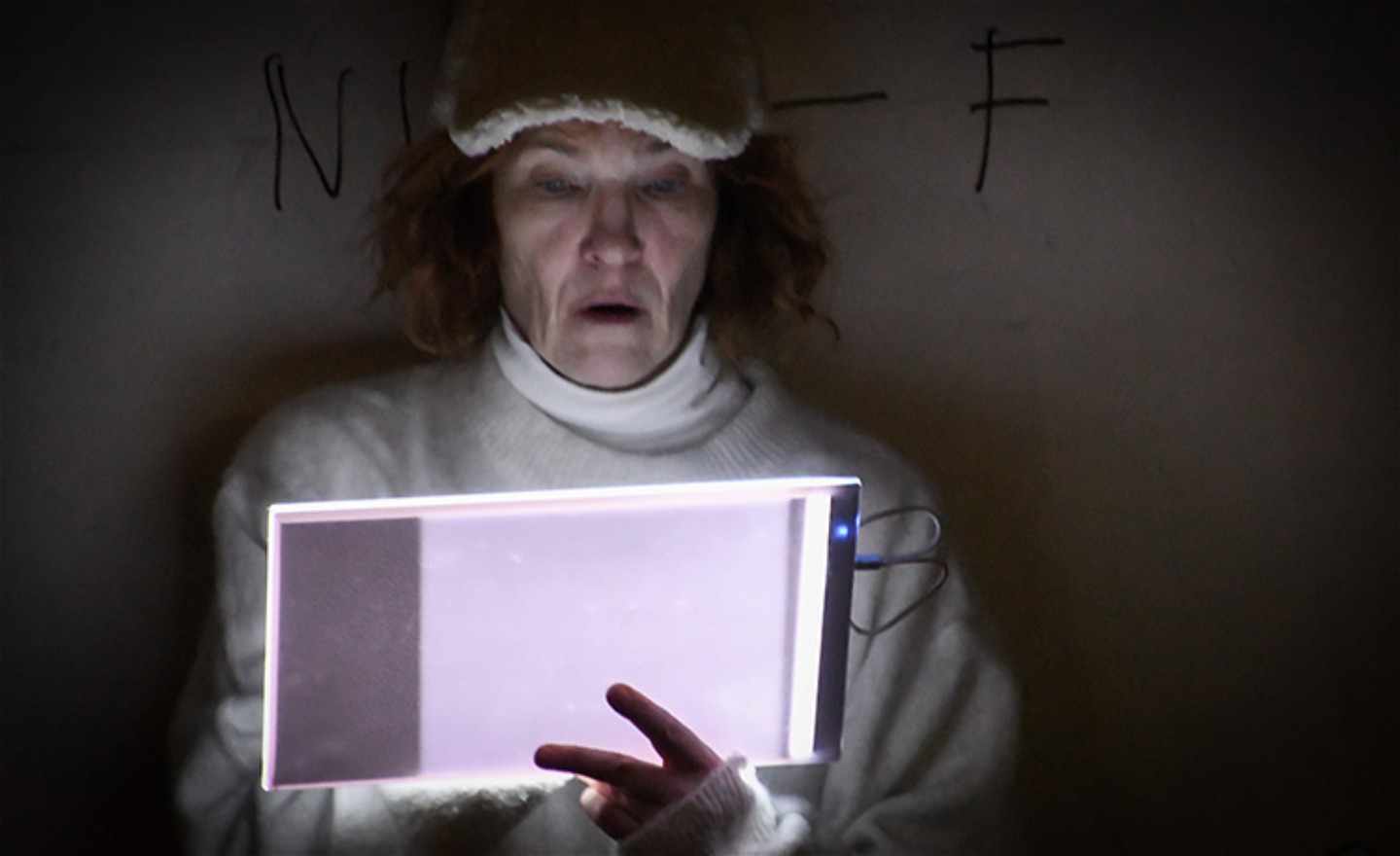 Skådespelare i vitt i mörkt rum vid en ljusplatta