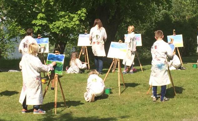 Fotografi av elever som målar friluftsmåleri vid stafflier utomhus