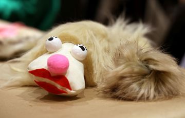 En handdocka med stor röd mun och rosa näsa.