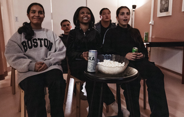 En grupp ungdomar med popcorn och läsk på bordet framför sig.