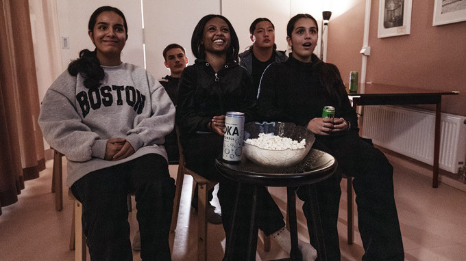 En grupp ungdomar med popcorn och läsk på bordet framför sig.