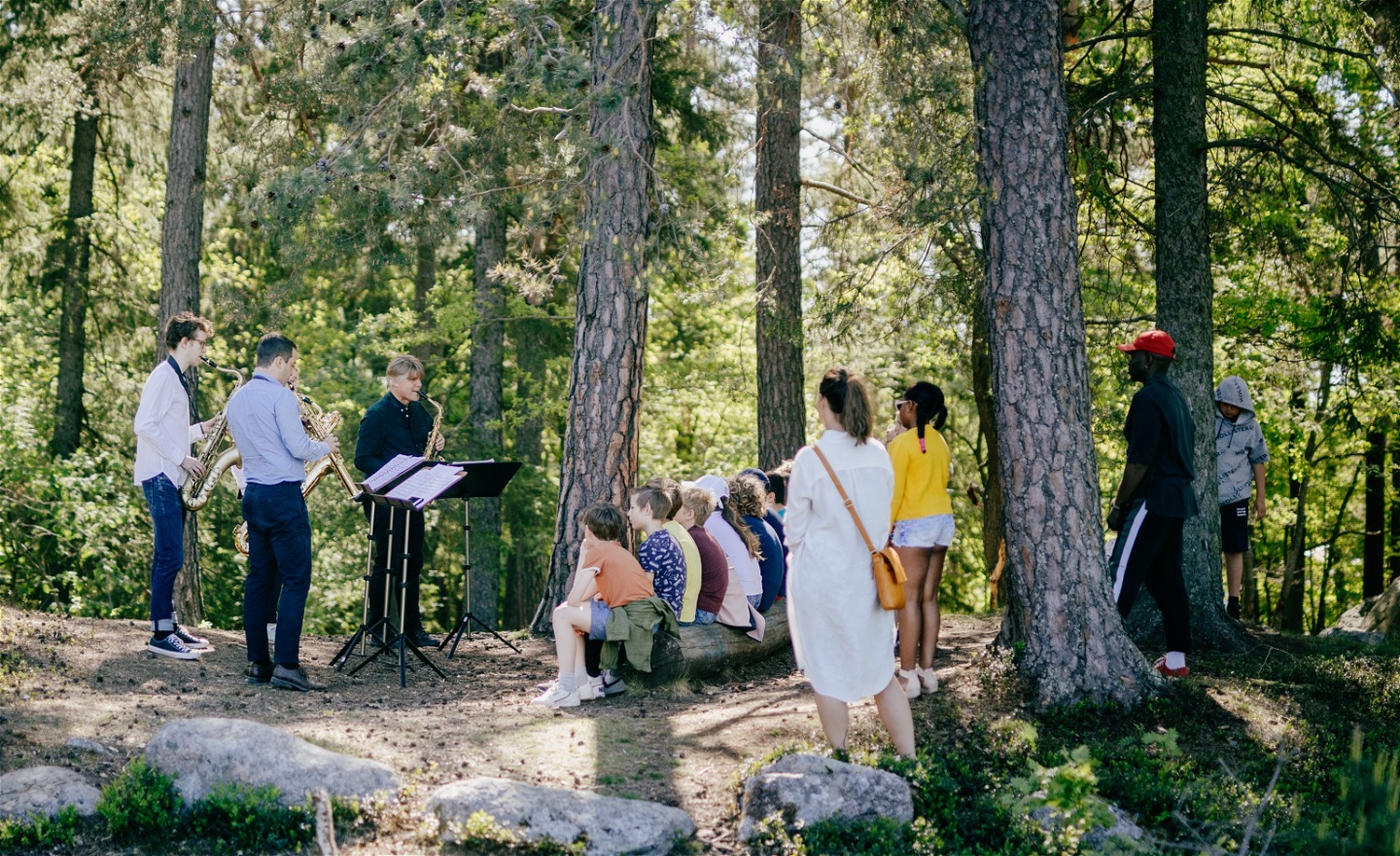 Saxofonister spelar för barn utomhus
