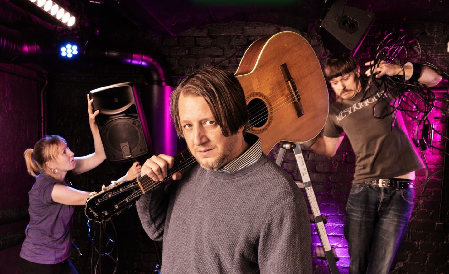 Man med gitarr och tekniker i bakgrunden