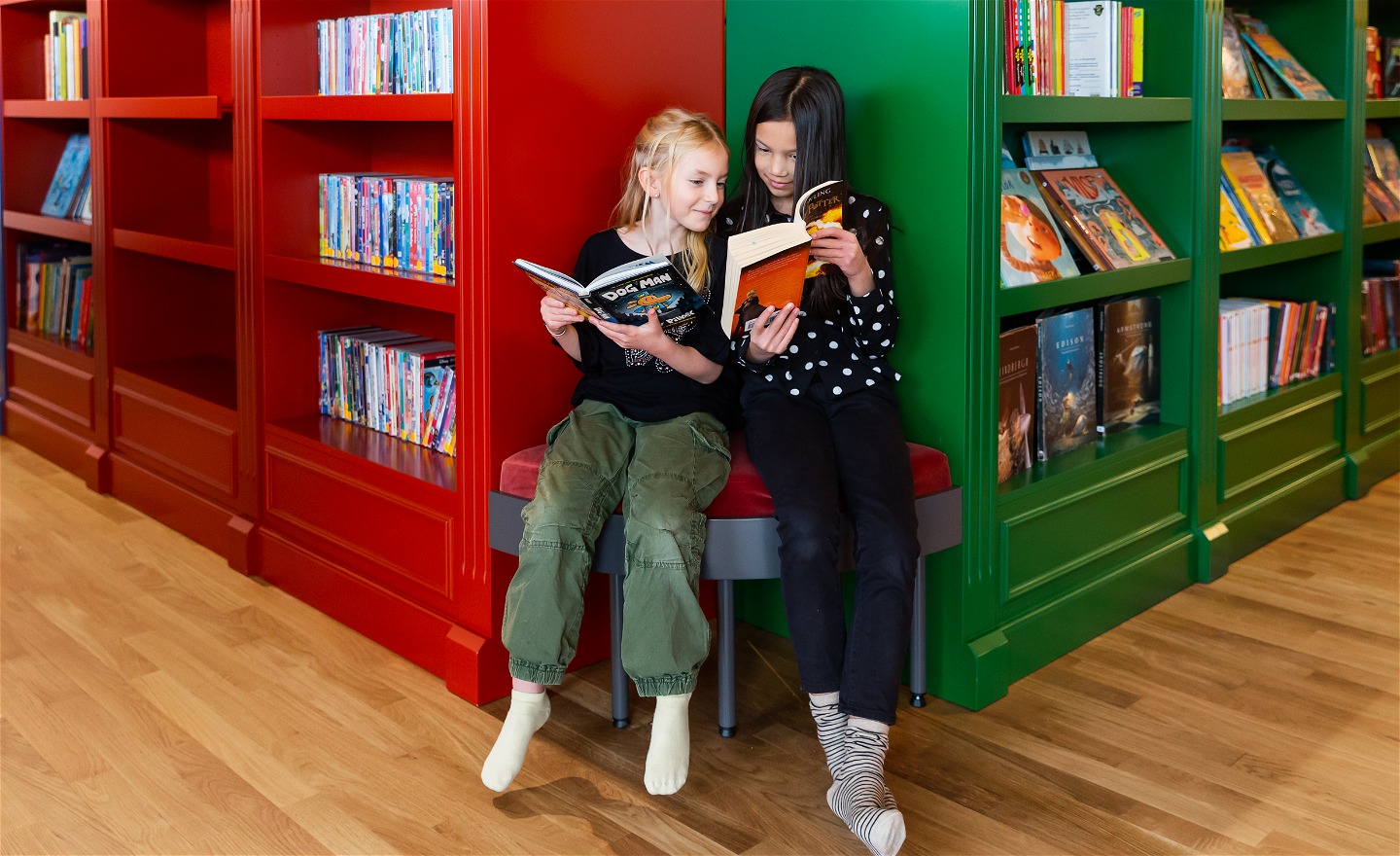 Två tjejer läser varsin bok i biblioteket Rum för Barn