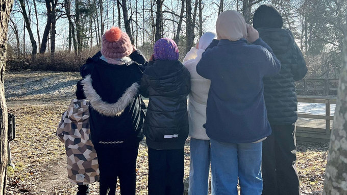 Sex elever tittar mot skogen med kikare.