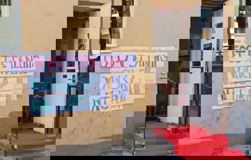 En röd matta leder in genom en dörr. På husfasaden finns en skylt med texten 