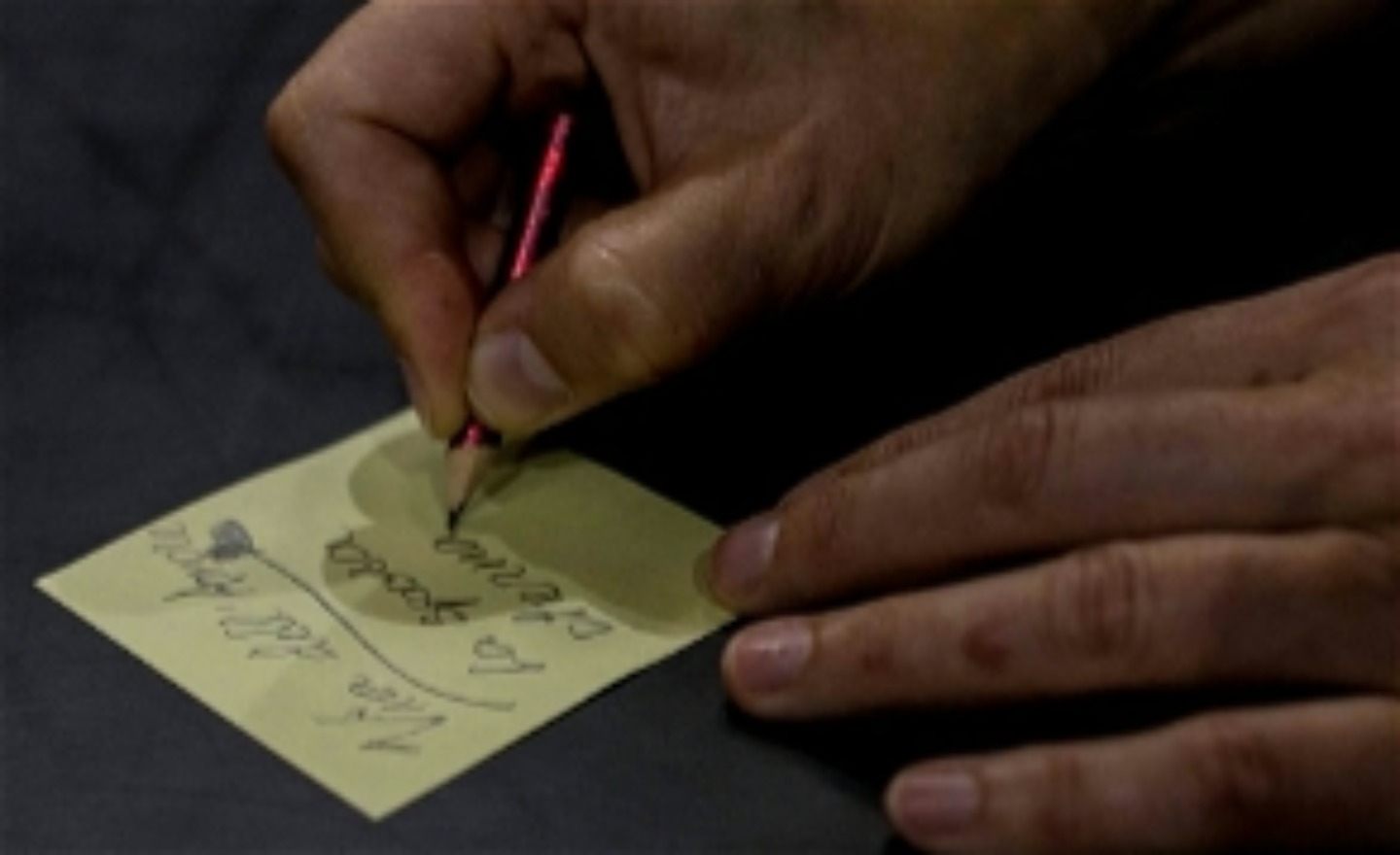 En hand som skriver på en postitlapp