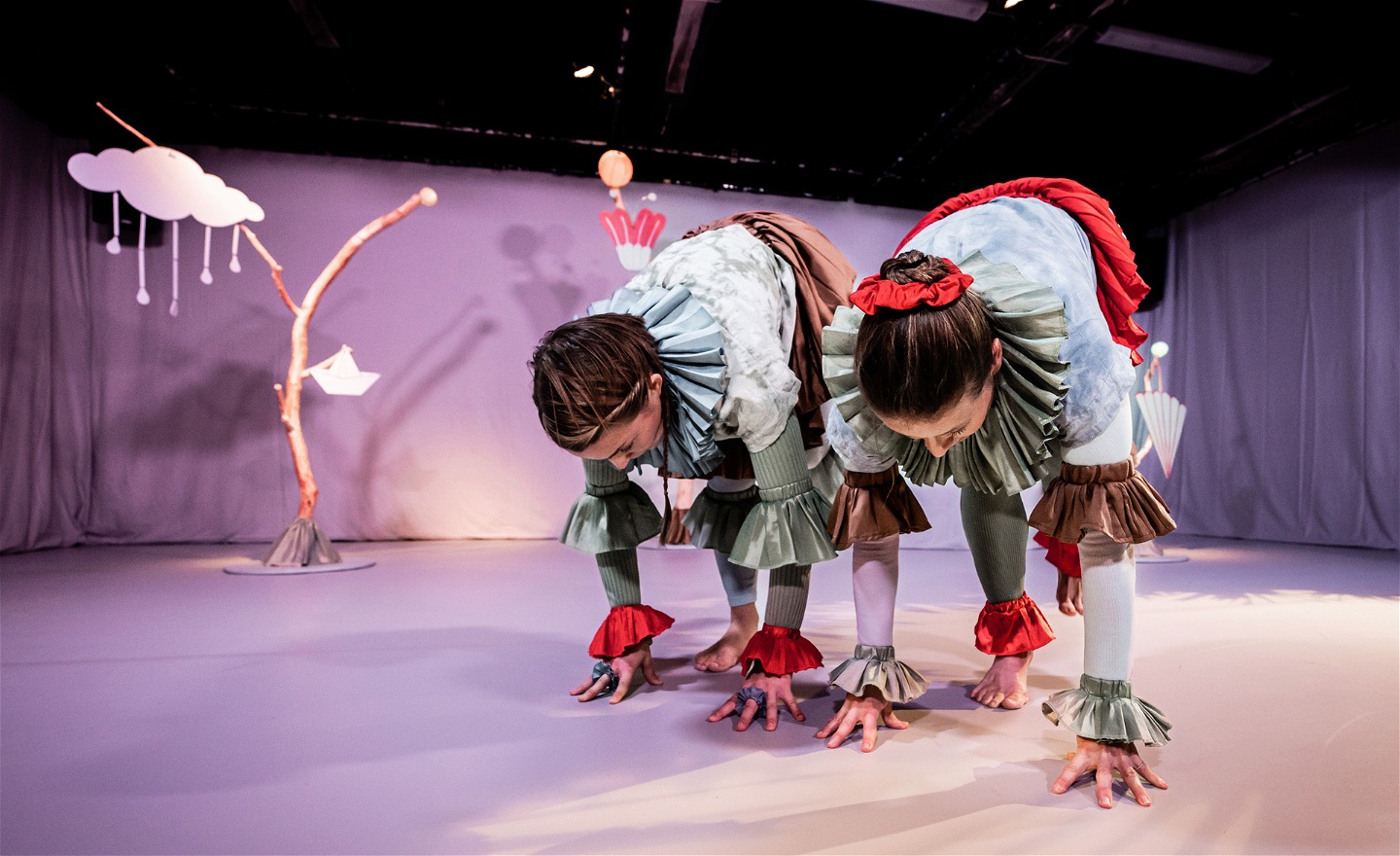 Dansarna Lisa och Åsa böjer sig långt fram och spretar med alla fingrar på golvet. 