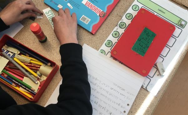 Ett barn klipper och klistrar.