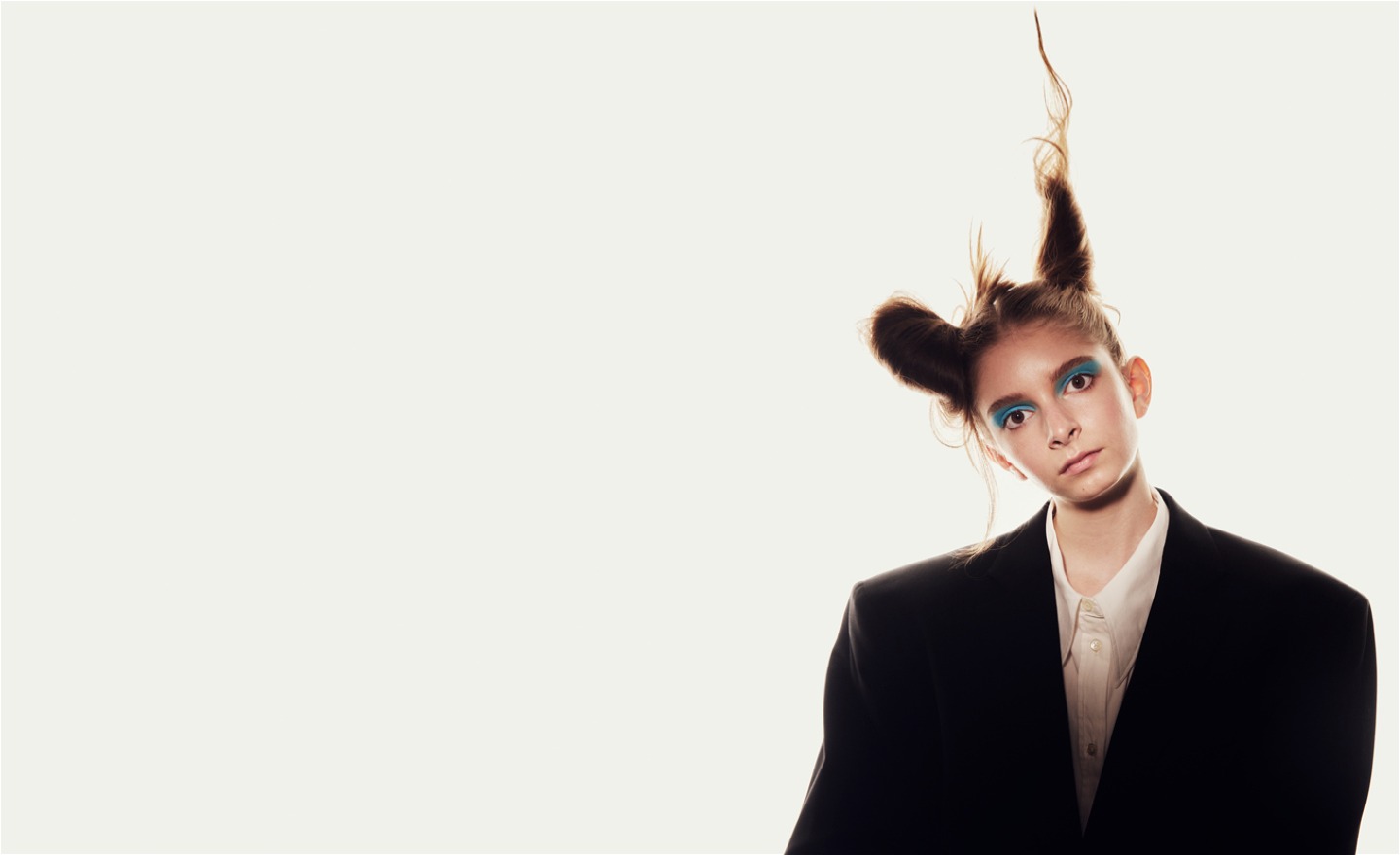 Flicka i vit skjorta, svart kavaj och yvig frisyr