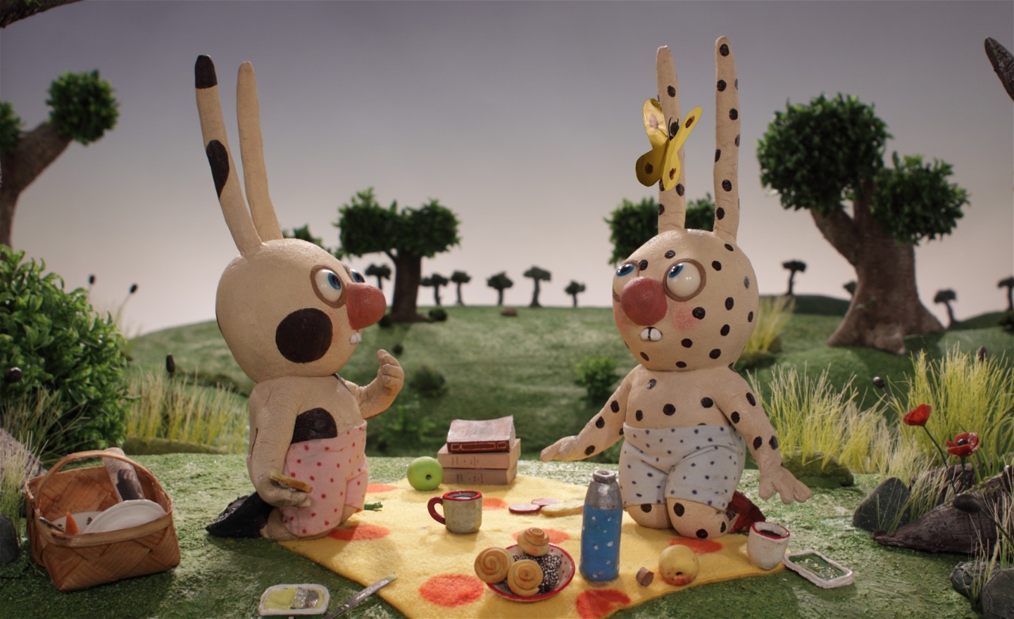 Två prickiga kaniner med långa öron äter pricknick på en prickig filt med prickig termos.