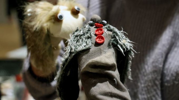 En person håller i två handdockor.