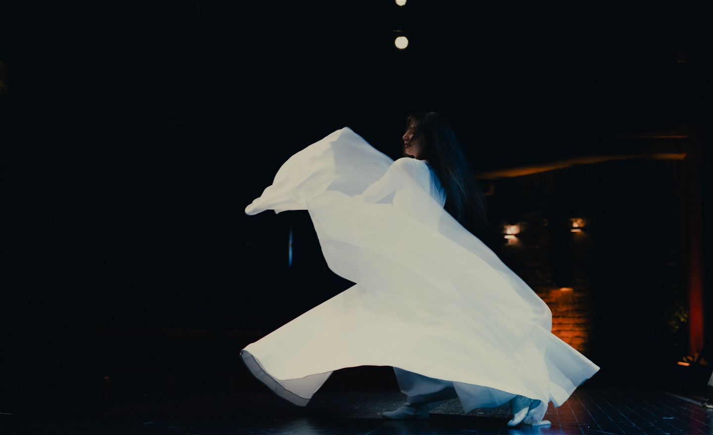 En bild på en dansare som bär vita stora kläder och dansar sufi-dans.