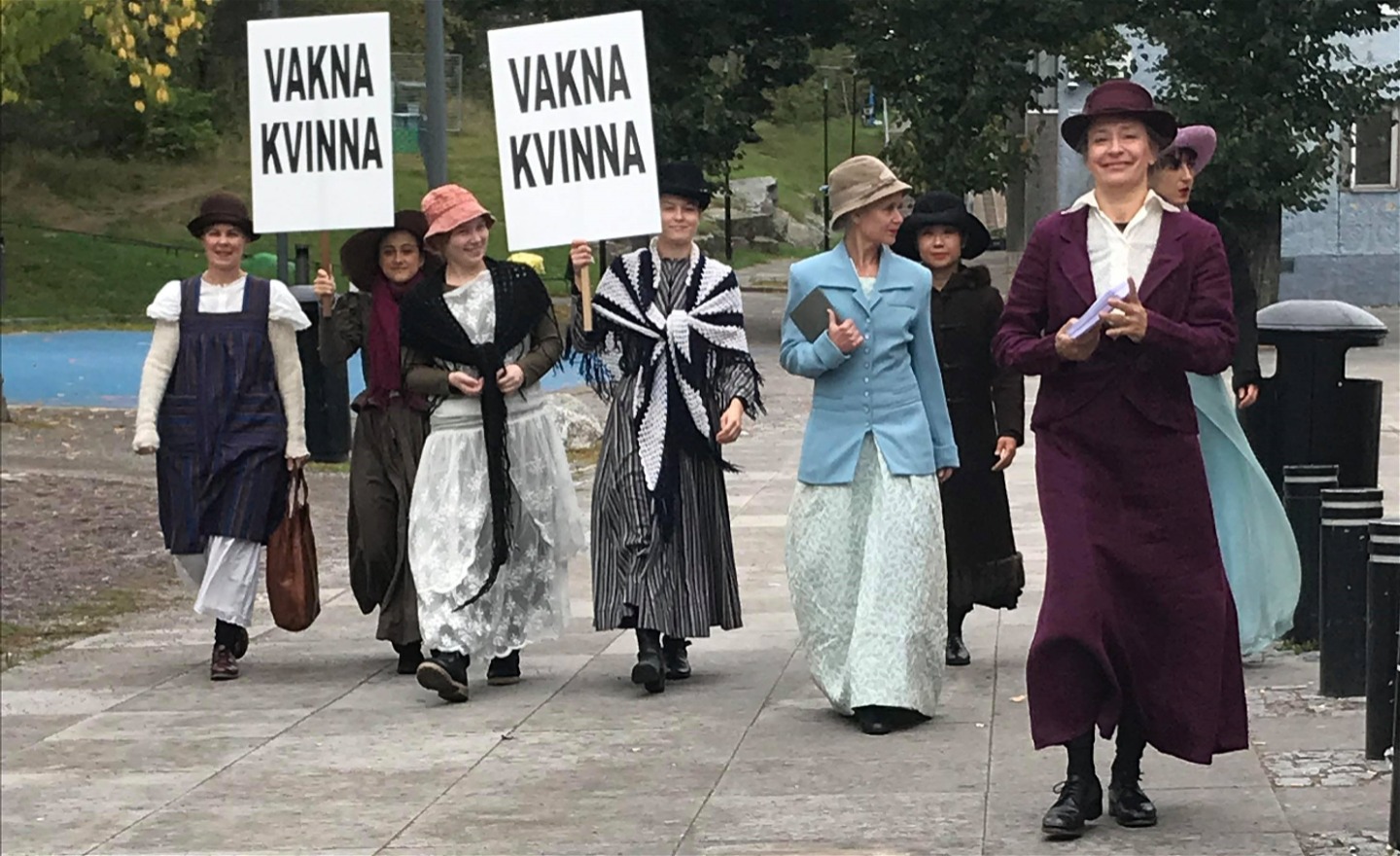 Kvinnor med plakat och kläder som för tankarna till de som demonstrerade för sin rösträtt 1921