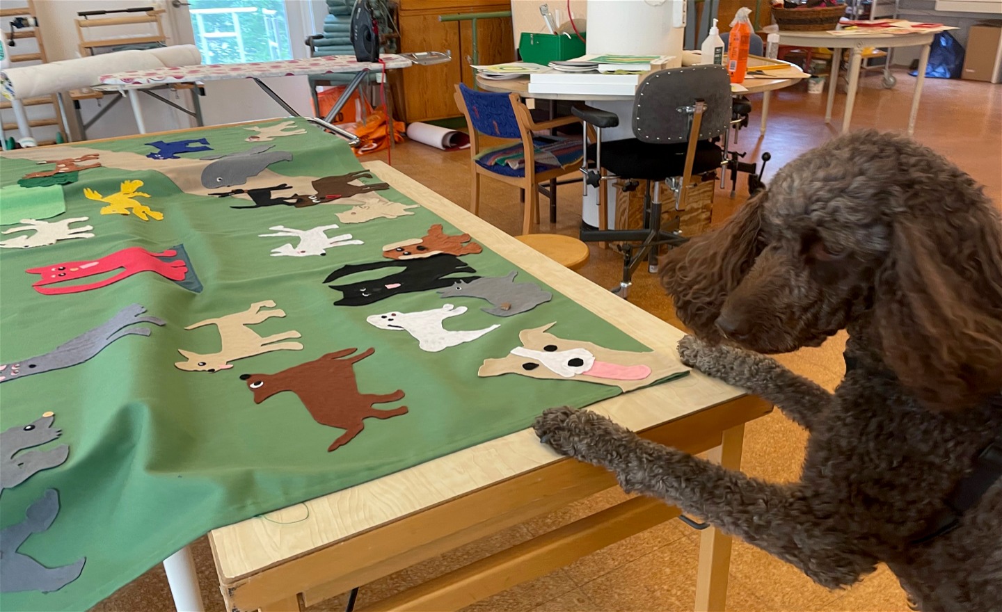 En brun hund visar ett textilkonstverk.