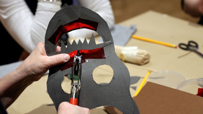 En person skapar en skuggspelsdocka i papper.