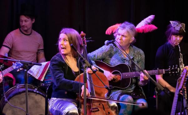 Emma spelar cello och sjunger/ropar, i bakgrunden Fredrik som spelar trummor och Cecilia som spelar gitarr 