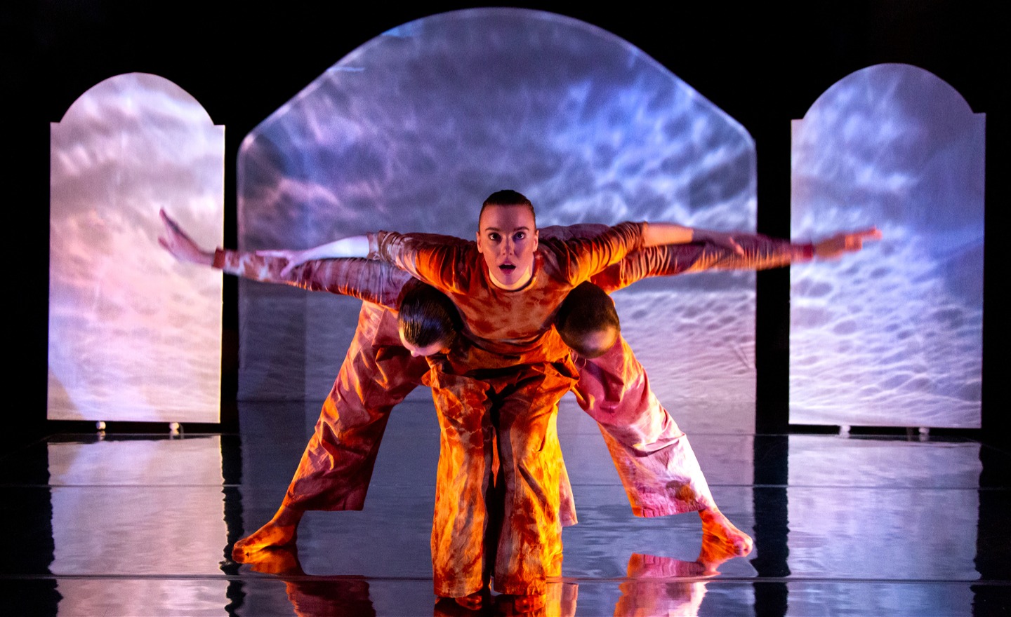 Tre personer formar med kropparna en fågel med utsträckta vingar