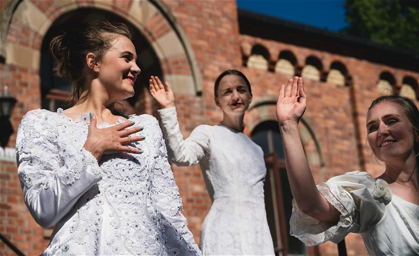 Tre dansare dansar utomhus i bröllopsklänningar