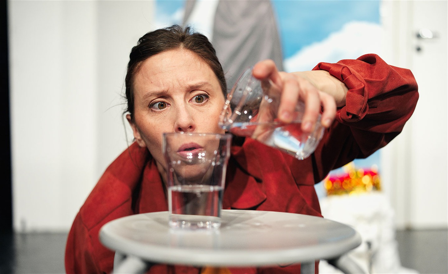 En person i röd skjorta fördelar vatten i två glas.